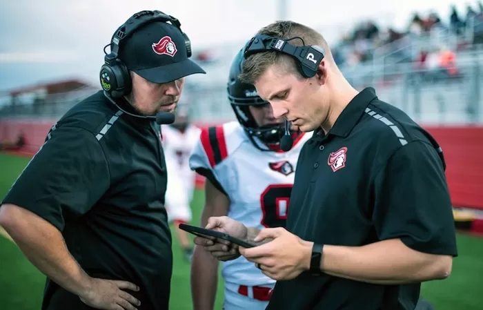 A coach holding a smartphone